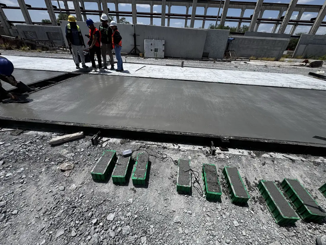 Green cube molds and a Sensytec data logger laid out beside a finished precast panel at Concremex Monterrey