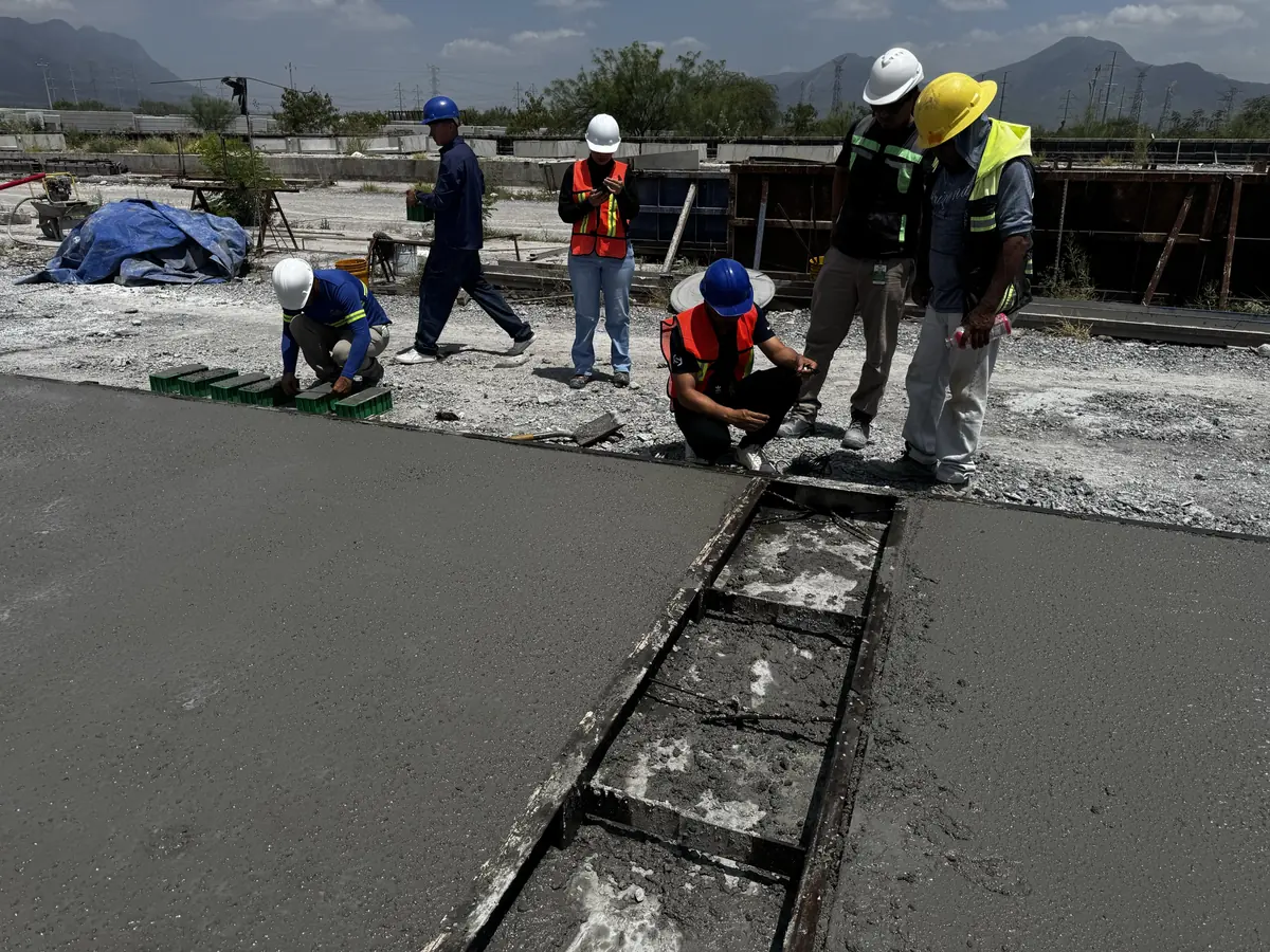Concremex crew finishing a freshly poured precast panel in Monterrey, with the sierra behind the casting yard