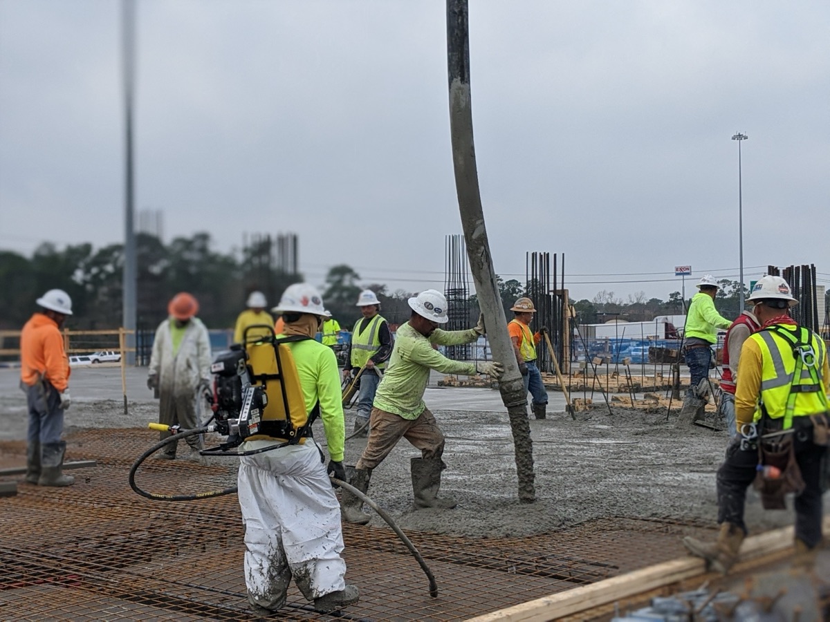 Construction crew pouring concrete on a rebar deck with Sensytec sensors embedded for real-time monitoring