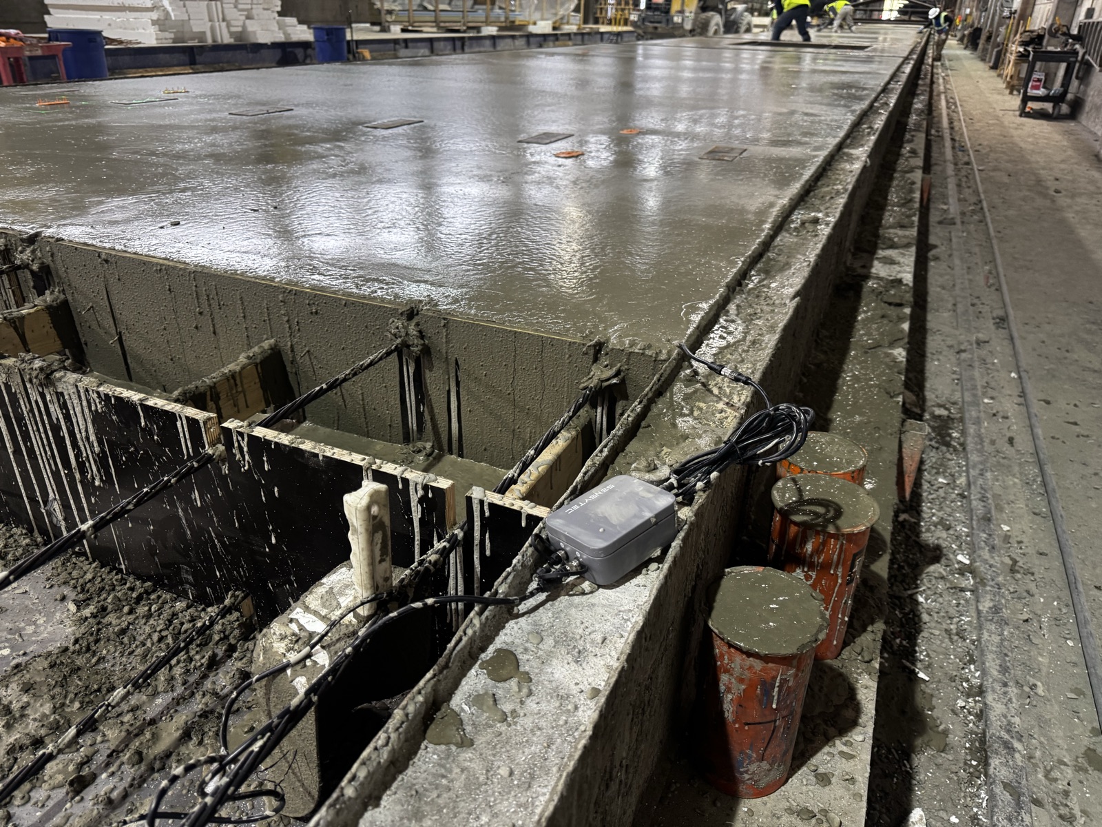 SensyCast wireless concrete sensor embedded in a prestressed bed alongside companion test cylinders